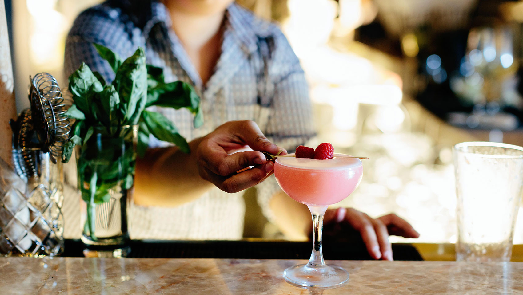 bartender garnishing a pink cocktail