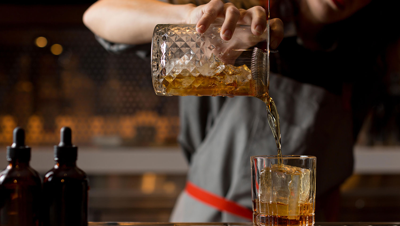 bartender pouring a whiskey cocktail