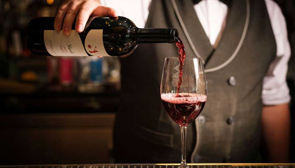 bartender pouring red wine into a glass
