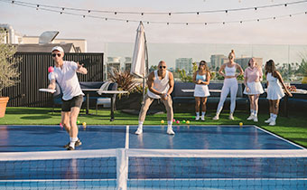 group of people playing pickleball on La Peer Hotel rooftop